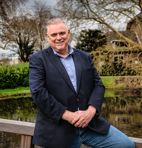 makelaar op een hek aan het water met groene park